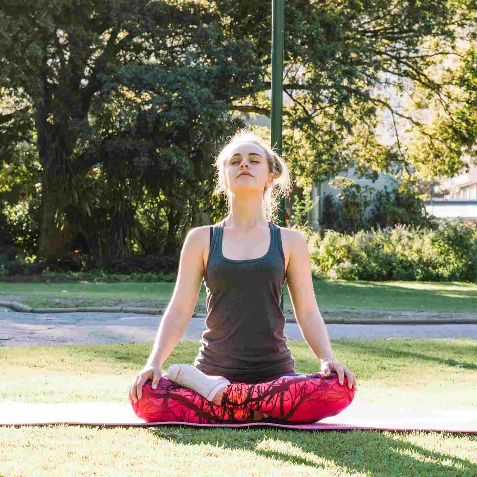 Woman sitting outdoors and breathing slowly on a mat